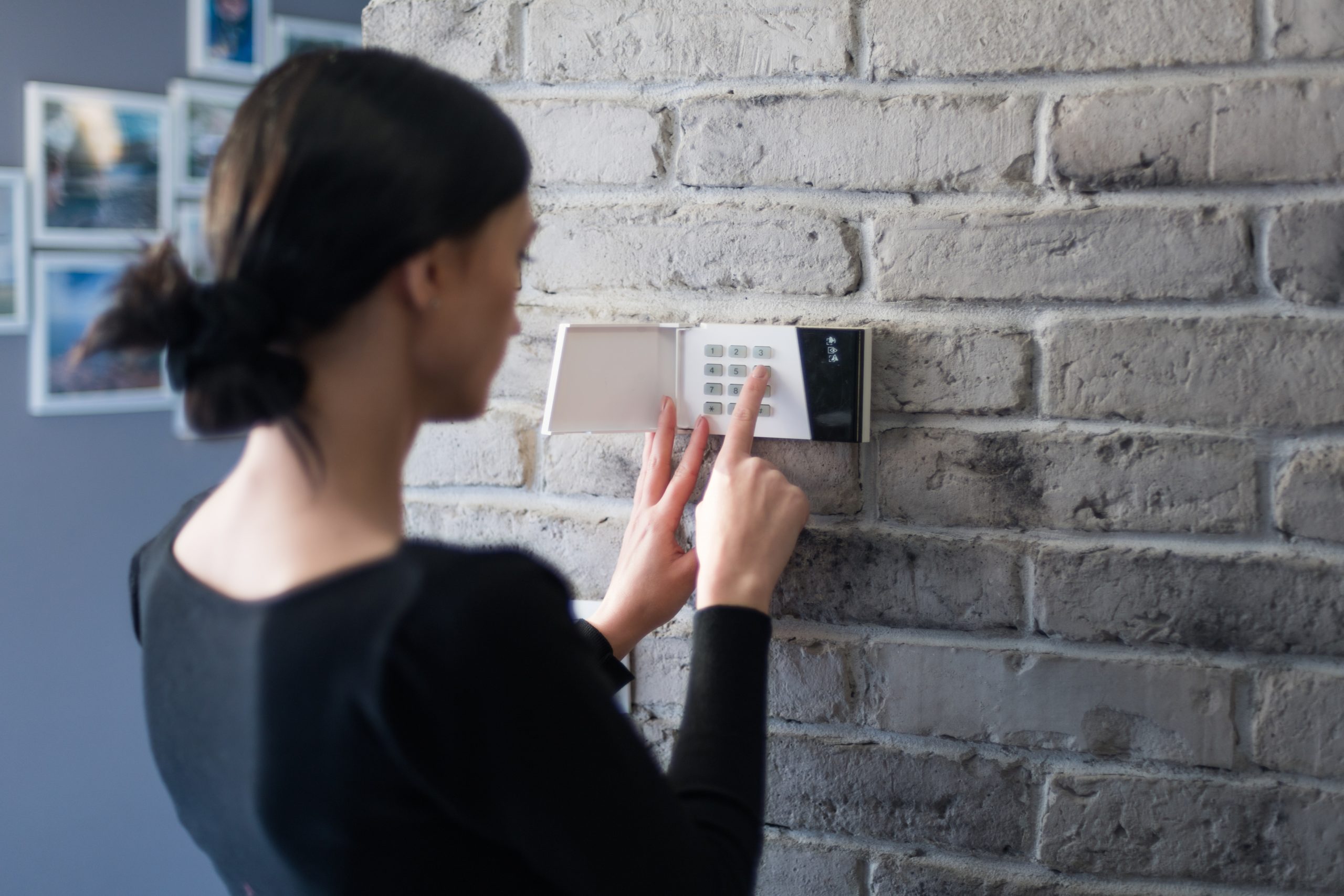 Woman operating an intruder alarm panel on a wall